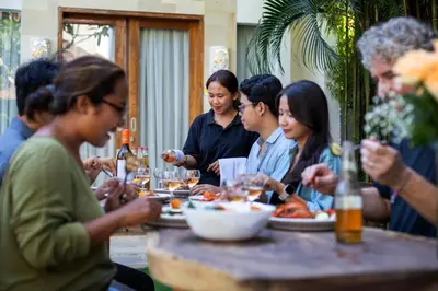 a group of people sitting at a table eating food at Best Location 7 Bed, 7,5 Bath Pool Villa, near beach in Kuta