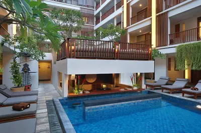 a swimming pool with a fireplace in a building at The Magani Hotel and Spa in Legian