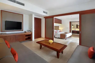 a living room with a couch and a bed and a television at The Magani Hotel and Spa in Legian