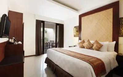 a hotel room with a large bed and a television at Best Western Kuta Villa in Kuta