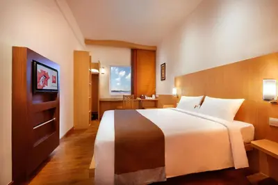 a hotel room with a large bed and a television at Ibis Bali Kuta in Kuta