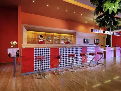 a bar with red and white bar stools at Ibis Bali Kuta in Kuta