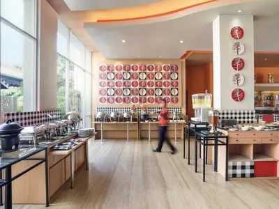 a person walking through a kitchen with red plates on the wall at Ibis Bali Kuta in Kuta