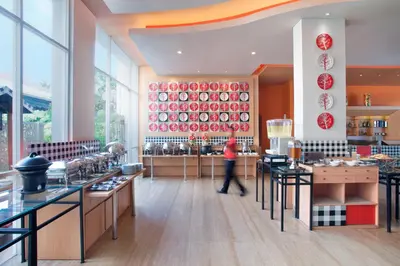 a person walking through a restaurant with red plates on the wall at Ibis Bali Kuta in Kuta