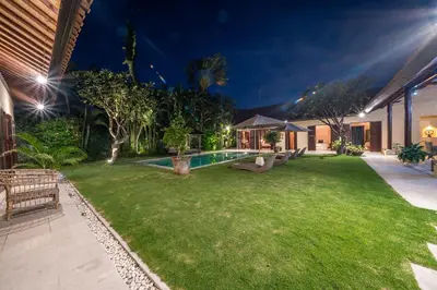 a backyard with a swimming pool at night at Rumi Villas in Seminyak