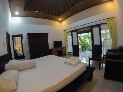 a bedroom with a large bed and a living room at Putu Guest House in Canggu