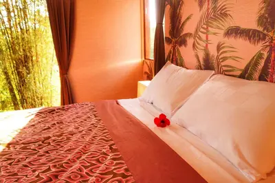 a bedroom with a bed with a red flower on it at Petit Tree in Seminyak