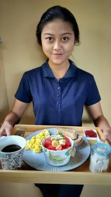 a woman sitting at a table with a tray of food at Petit Tree in Seminyak