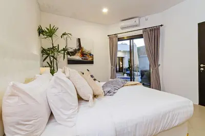 a bedroom with a large white bed with pillows at Villa Serasi in Canggu