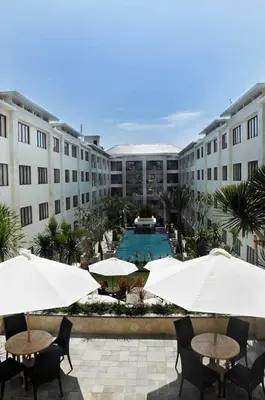 a courtyard with tables and umbrellas and a swimming pool at Kuta Luxury Residence in Kuta