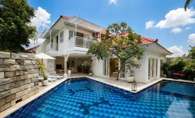 a villa with a swimming pool in front of a house at Villa Marronniers in Seminyak