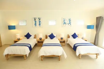 a room with four beds with blue and white sheets at Villa Marronniers in Seminyak