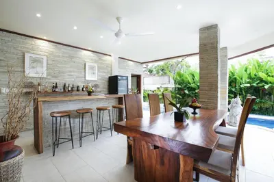 a kitchen and dining room with a wooden table and chairs at Villa Chambertin in Seminyak
