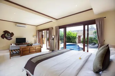 a bedroom with a large white bed and a television at Villa Chambertin in Seminyak