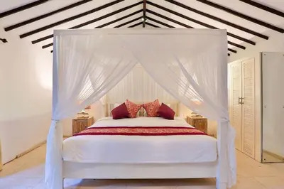 a bedroom with a white canopy bed with red pillows at Villa Champagne in Seminyak