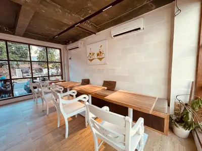 a restaurant with wooden tables and white chairs at La Belle Villa in Seminyak