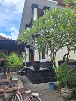 a pink bike parked in front of a house with trees at Jukung Villas Kuta in Kuta