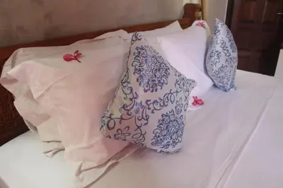 a bed with blue and white pillows on it at Jukung Villas Kuta in Kuta