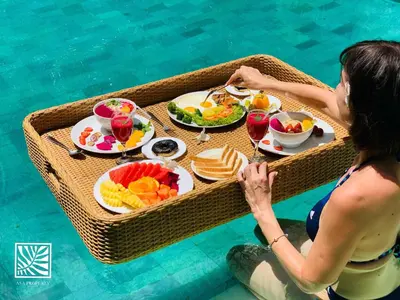 a woman holding a tray of food in a swimming pool at Beach Axis Villa, Seminyak in Seminyak