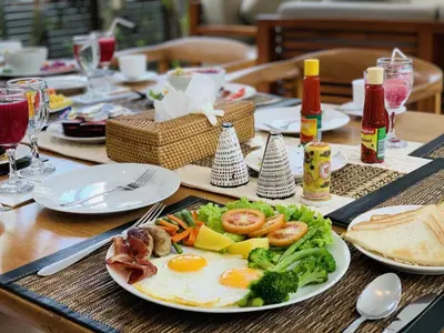 a table with a plate of food with eggs and broccoli at Beach Axis Villa, Seminyak in Seminyak