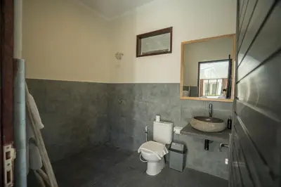 a bathroom with a toilet and a sink and a mirror at The Catur Villa Seminyak in Seminyak