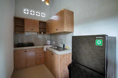 a kitchen with wooden cabinets and a black refrigerator at The Catur Villa Seminyak in Seminyak