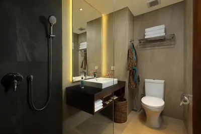 a bathroom with a toilet and a sink and a mirror at Anja Jimbaran in Jimbaran