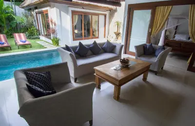 a living room with couches and a table and a pool at Villa Kamboja Senior in Legian
