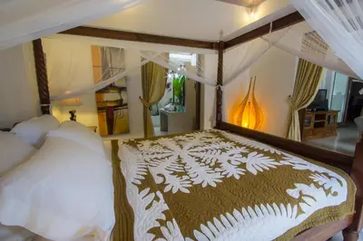a bedroom with a canopy bed with white pillows at Villa Kamboja Senior in Legian