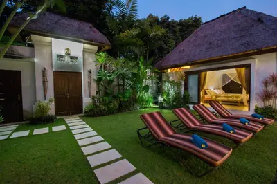 a yard with lounge chairs on the grass at Villa Kamboja Senior in Legian
