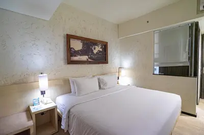 a bedroom with a large white bed and a window at The Akmani Legian in Legian