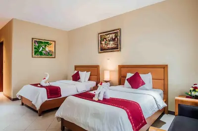 two beds in a hotel room with swans on them at Kuta Puri Bungalows, Villas and Resort in Kuta