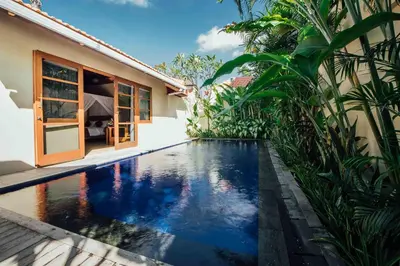 a swimming pool in front of a house at Kuta Puri Bungalows, Villas and Resort in Kuta