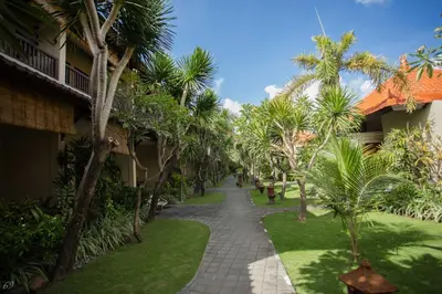 a walkway through the courtyard of a resort with palm trees at Kuta Puri Bungalows, Villas and Resort in Kuta