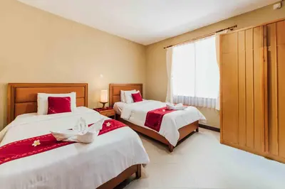 a bedroom with two beds with red and white sheets at Kuta Puri Bungalows, Villas and Resort in Kuta