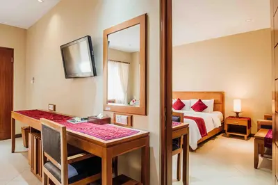 a bedroom with a bed and a table and a mirror at Kuta Puri Bungalows, Villas and Resort in Kuta