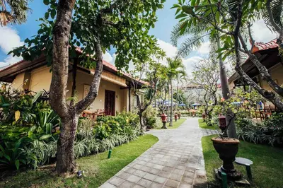 a walkway in front of a building with trees at Kuta Puri Bungalows, Villas and Resort in Kuta