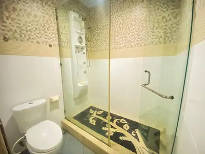a bathroom with a toilet and a glass shower at Dedy Beach Inn in Kuta