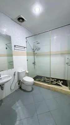 a bathroom with a toilet and a glass shower at Dedy Beach Inn in Kuta