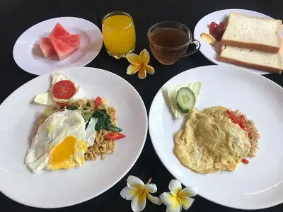 a table with plates of food and drinks and flowers at Agus Beach Inn in Kuta