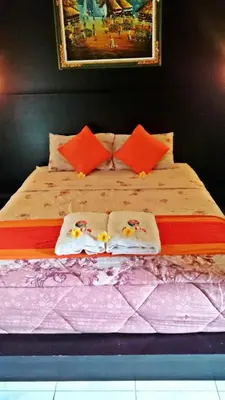 a large bed with orange pillows and a painting on the wall at Agus Beach Inn in Kuta