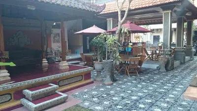 a building with chairs and tables and umbrellas at Agus Beach Inn in Kuta