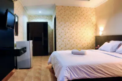 a bedroom with a large white bed and a television at Agus Beach Inn in Kuta