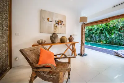 a room with a chair and a table with an orange pillow at Villa Lagoon Canggu in Canggu