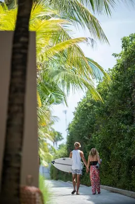 two women walking down a sidewalk holding a surfboard at One Eleven in Seminyak