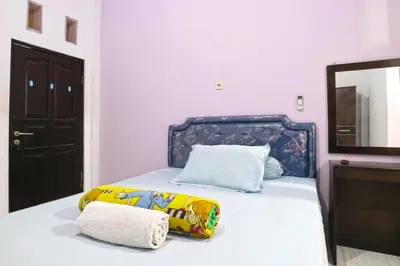 a bedroom with a bed with a dresser and a mirror at Micost Homestay in Denpasar