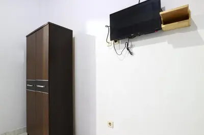 a tv hanging on a wall next to a cabinet at Micost Homestay in Denpasar