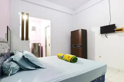 a white room with a bed with a pillow on it at Micost Homestay in Denpasar