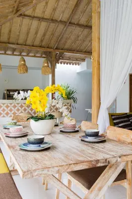 a wooden table with plates and yellow flowers on it at Villa Orked 1 in Seminyak