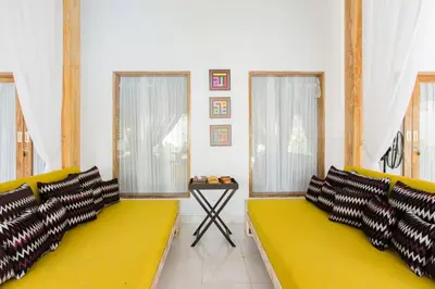 a living room with a yellow couch and windows at Villa Orked 1 in Seminyak